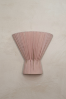 Pink pleated fabric wall lamp on a beige wall