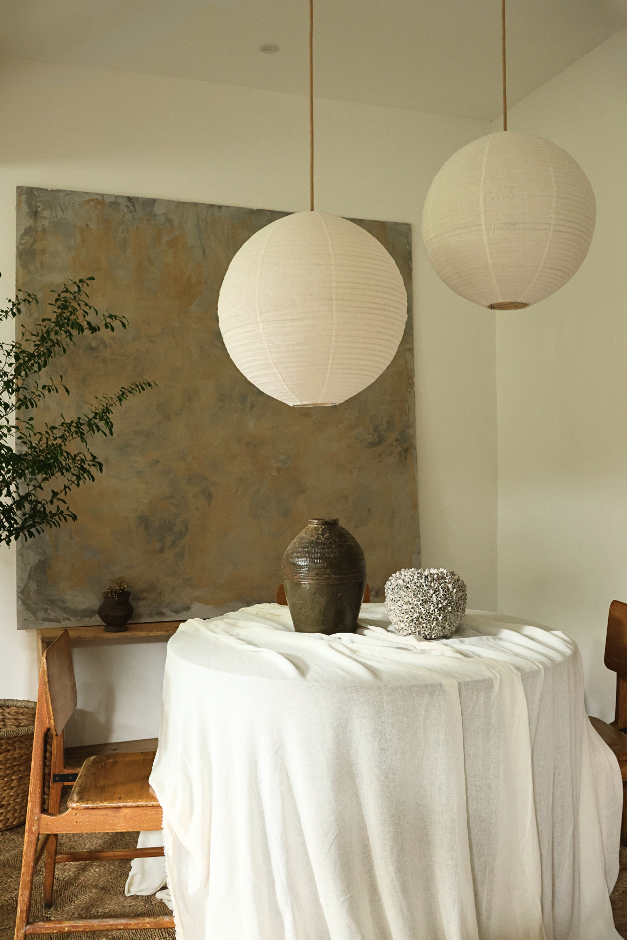 Two round linen lanterns hanging above a table with decorative items in a room.