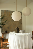 Two round linen lanterns hanging above a table with decorative items in a room.