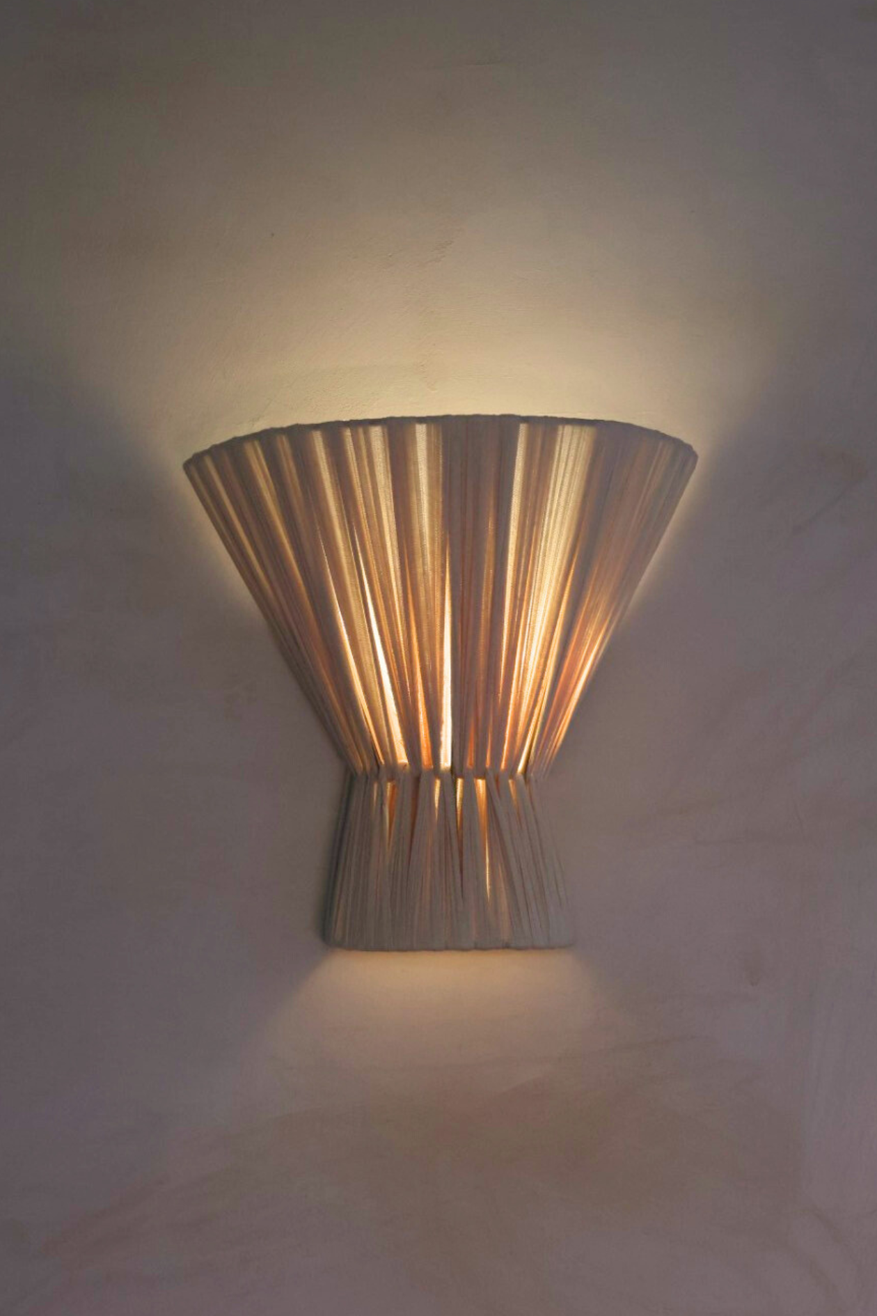 Decorative wall sconce casting a warm glow on a textured wall.