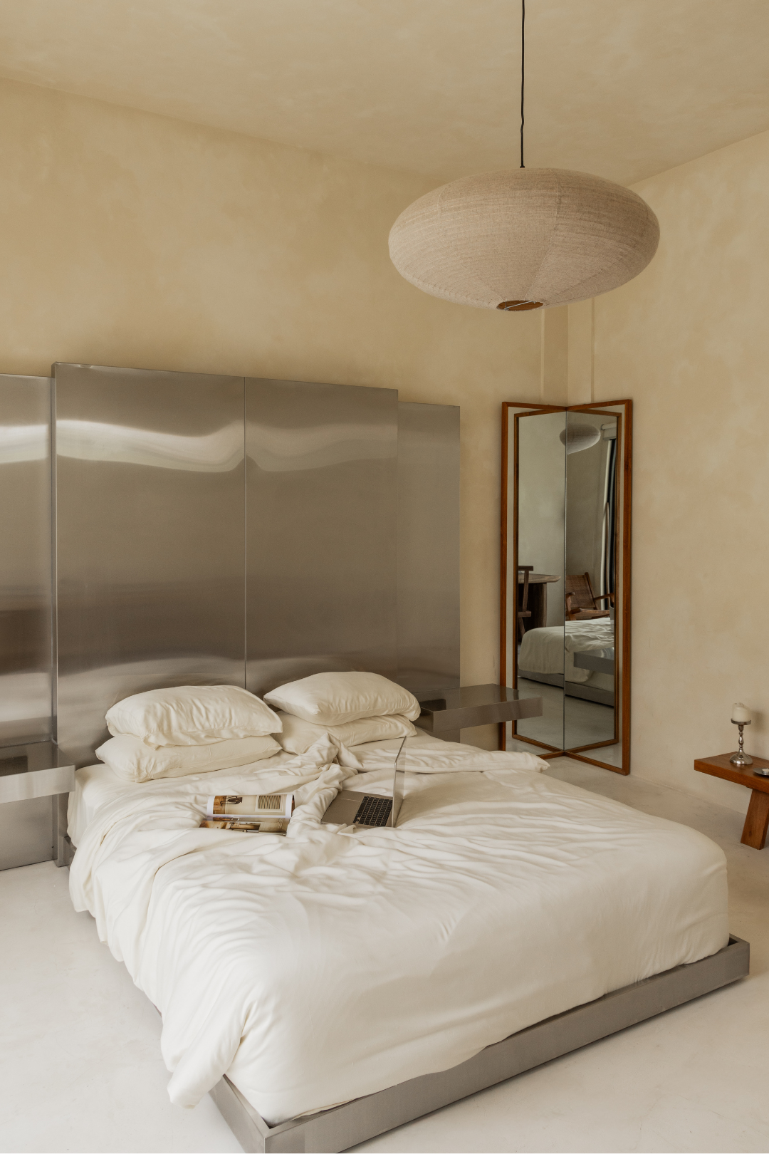 Modern bedroom with a large bed, mirror, and minimal decor.