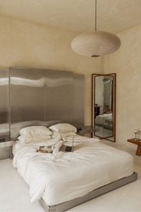 Modern bedroom with a large bed, mirror, and minimal decor.