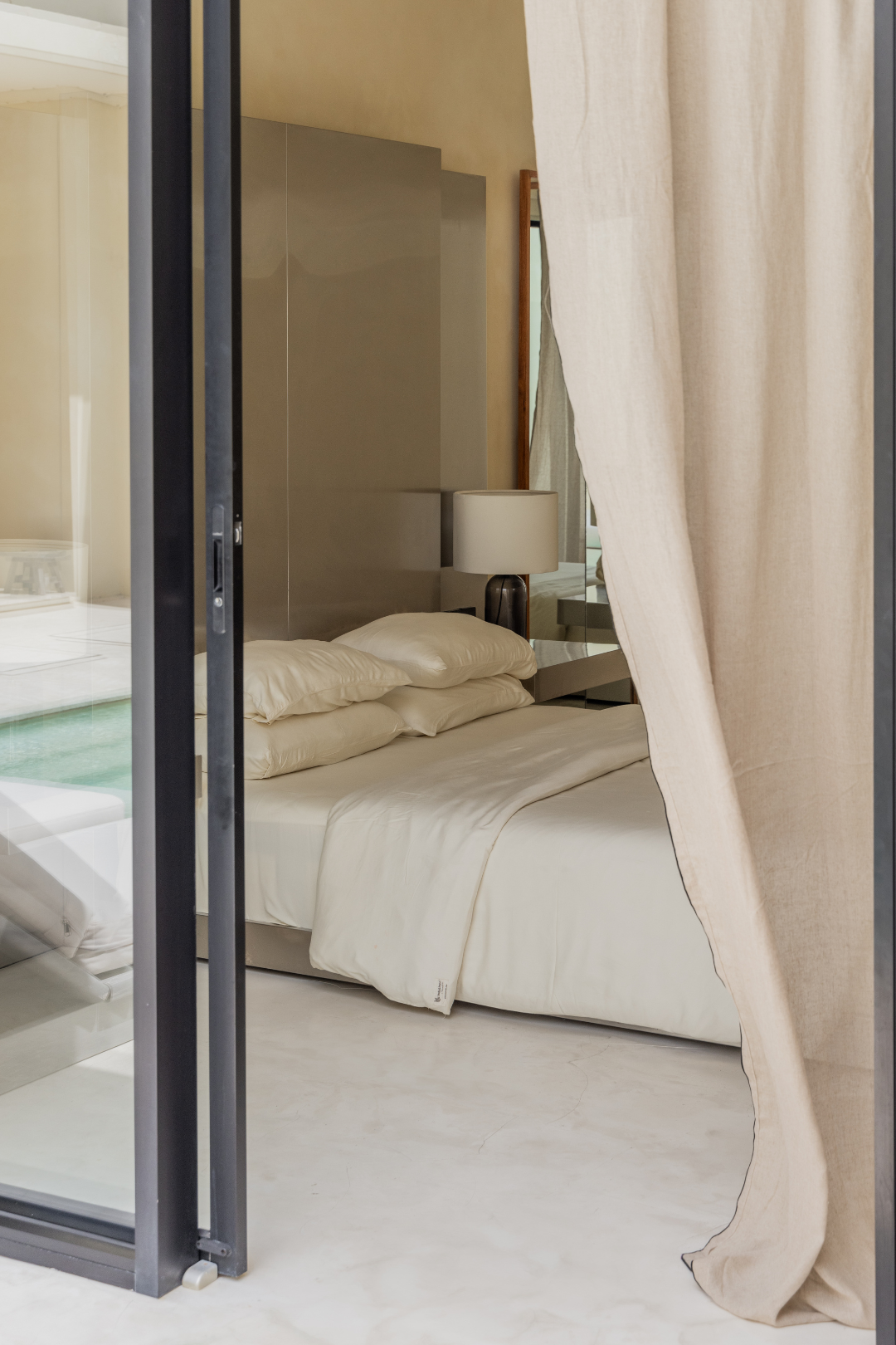Bedroom with a bed and curtains, visible through a glass door.