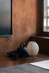 Decorative items including a black teapot and a white paper lantern on a wooden floor.