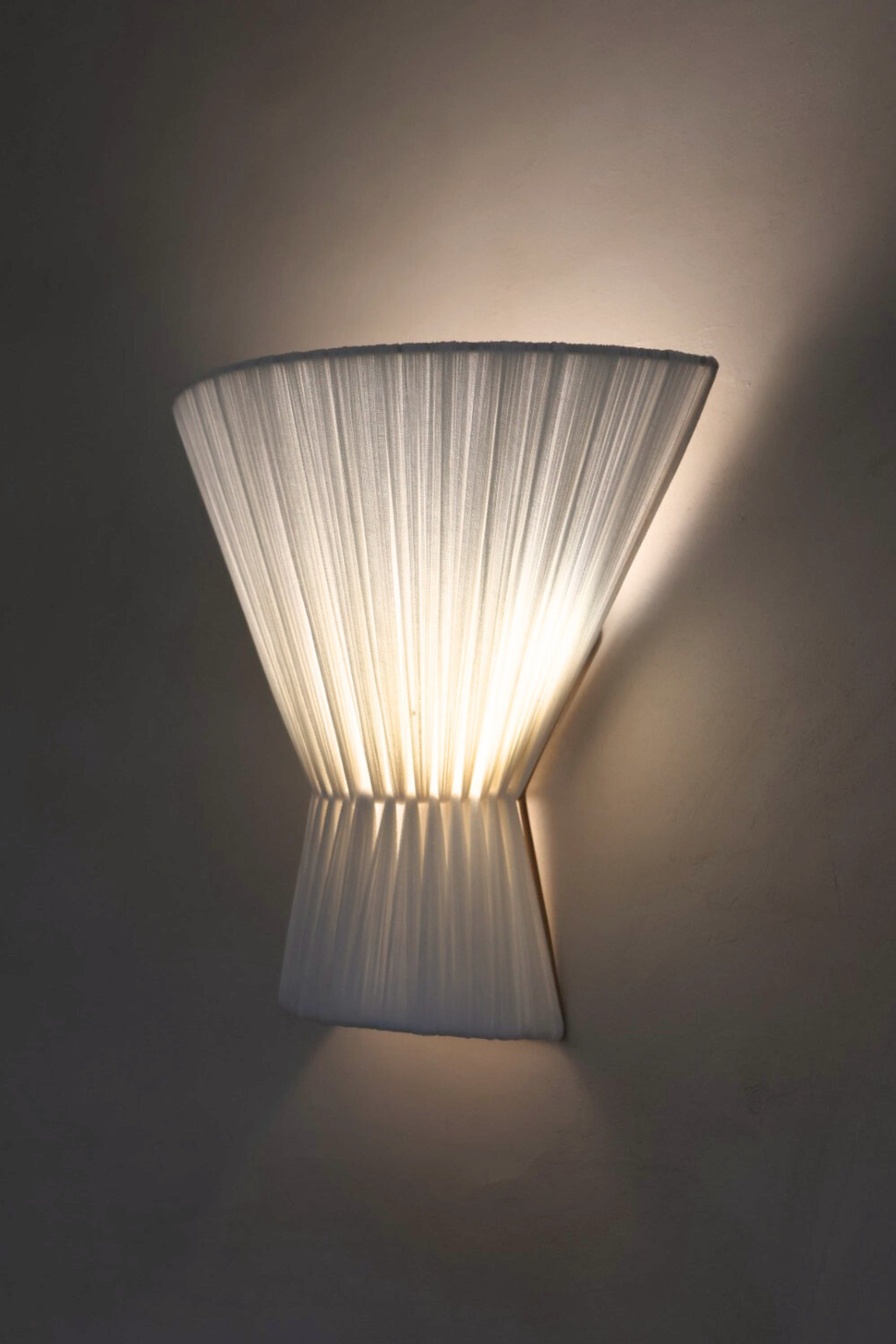 Wall-mounted lamp with pleated design on a dark background