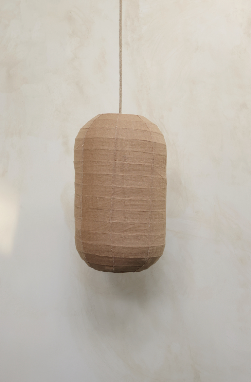 A bronze color linen shade designed for pendant lighting, displayed against a wooden background.