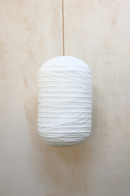 A white capsule-shape linen shade designed for pendant lighting, displayed against a neutral background.