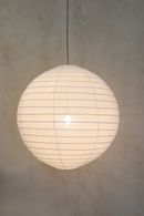 A white round linen light shade with a woven rattan frame, hanging against a neutral background.
