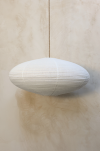 A pendant lamp with a linen shade in an almond-shaped silhouette, displayed against a light background.