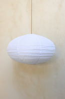 A beige linen dome pendant shade hanging against a wooden background.